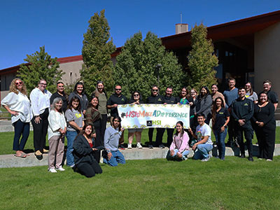 Students and teachers holding an HSI Sign on campus