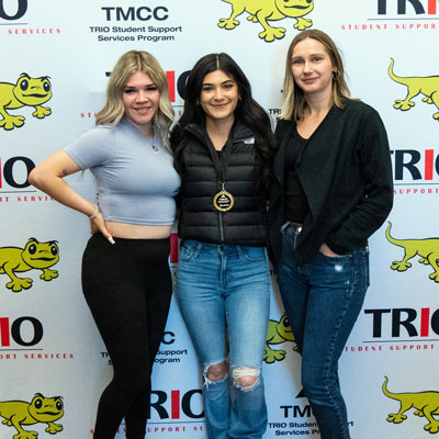 TMCC TRIO graduates standing in front of a branded backdrop