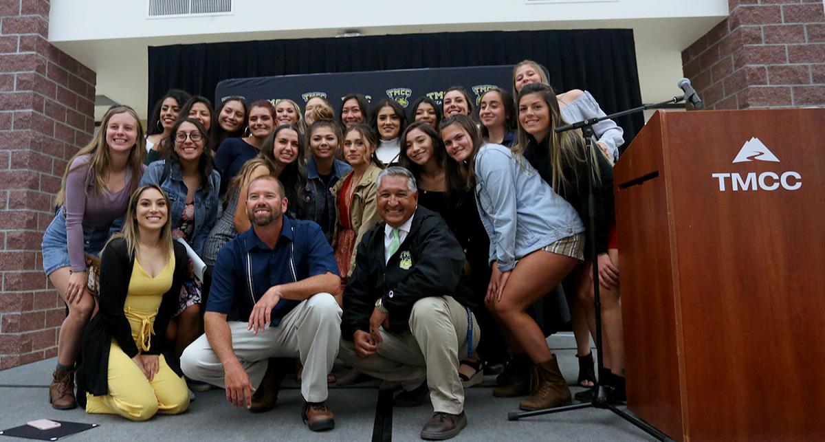 Women's soccer team posing with their coaches.