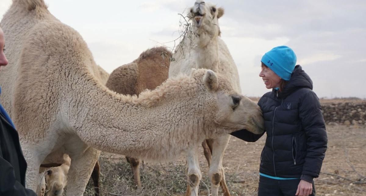 Namie standing next to two camels.