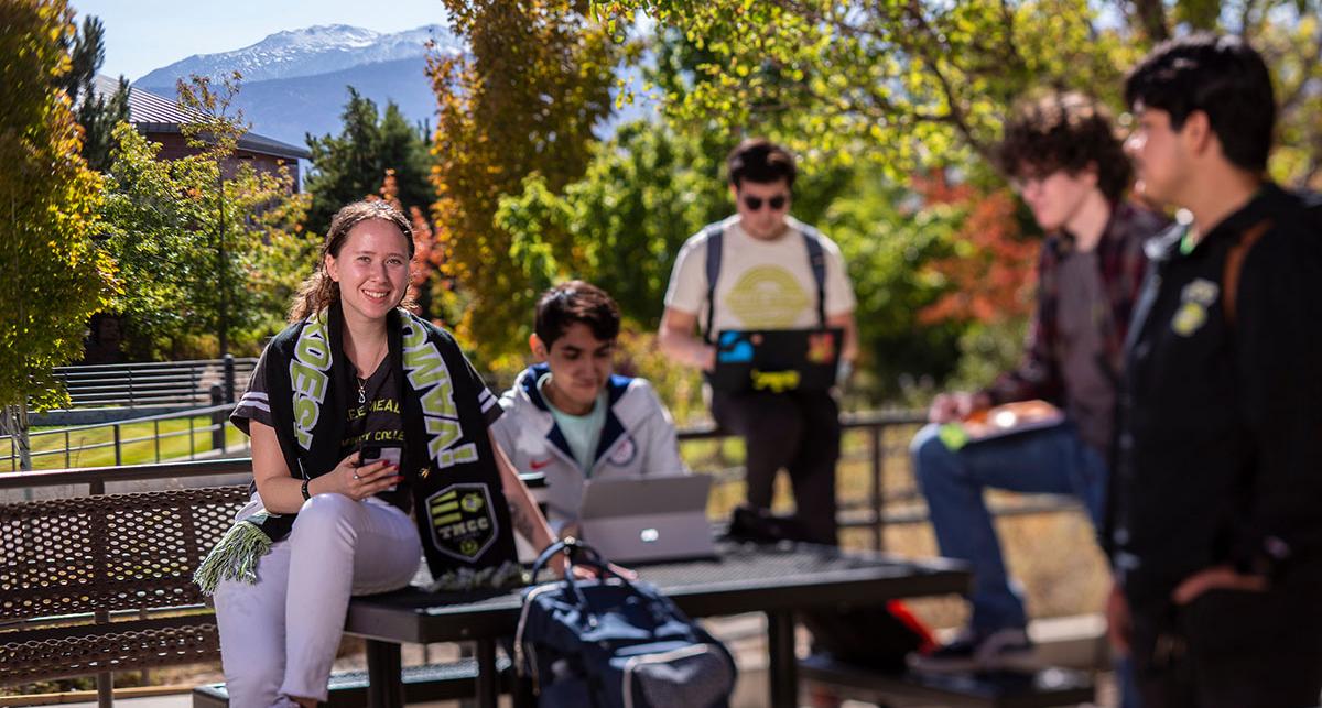 Group of students sitting outdoors near the cafe.