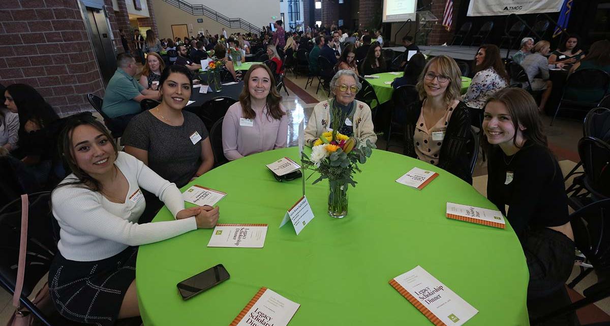 Donor Jean Myles with scholarship recipients sitting at a table.