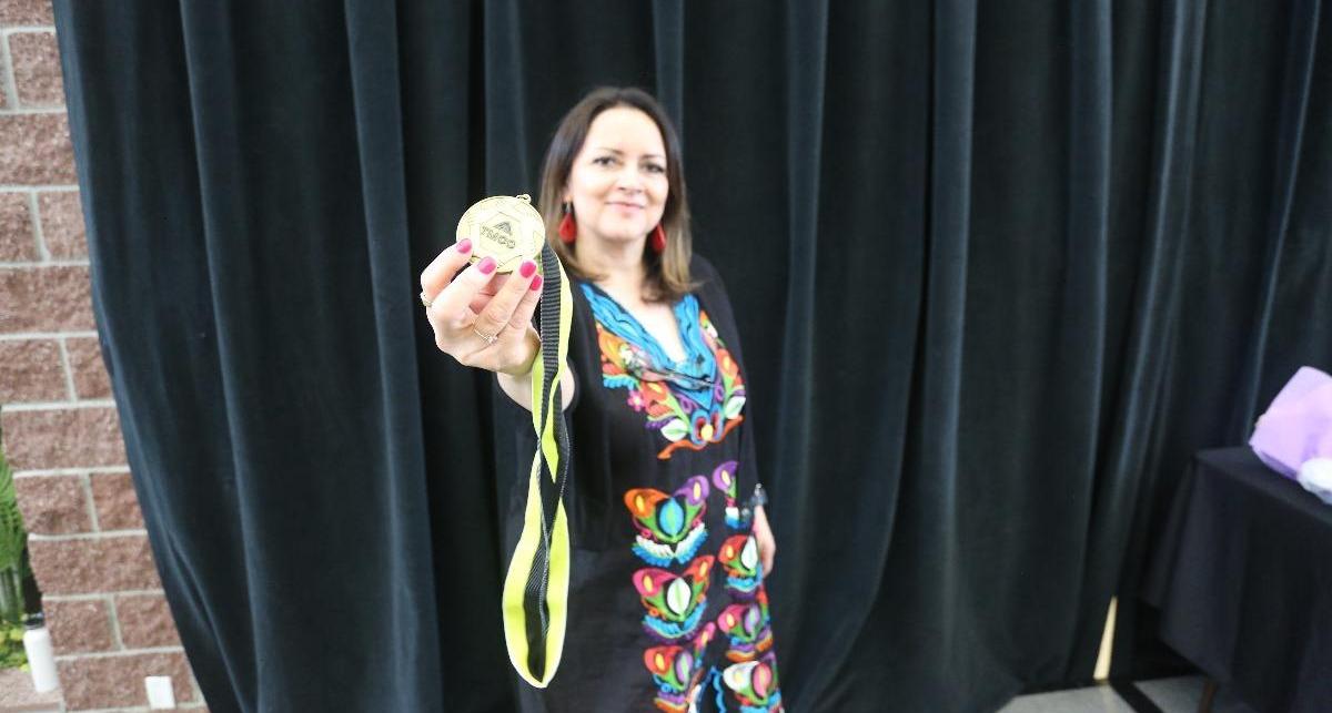 Juana Reynoza-Gomez holds up the Unity Graduation medallion.