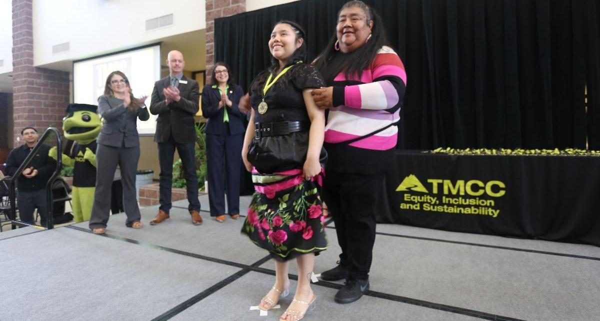 Younger graduate is bestowed with a medal from her family member.