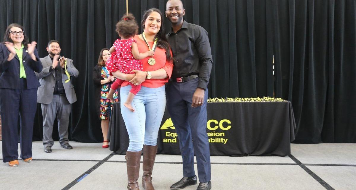 Graduate stands on stage with her happy family.