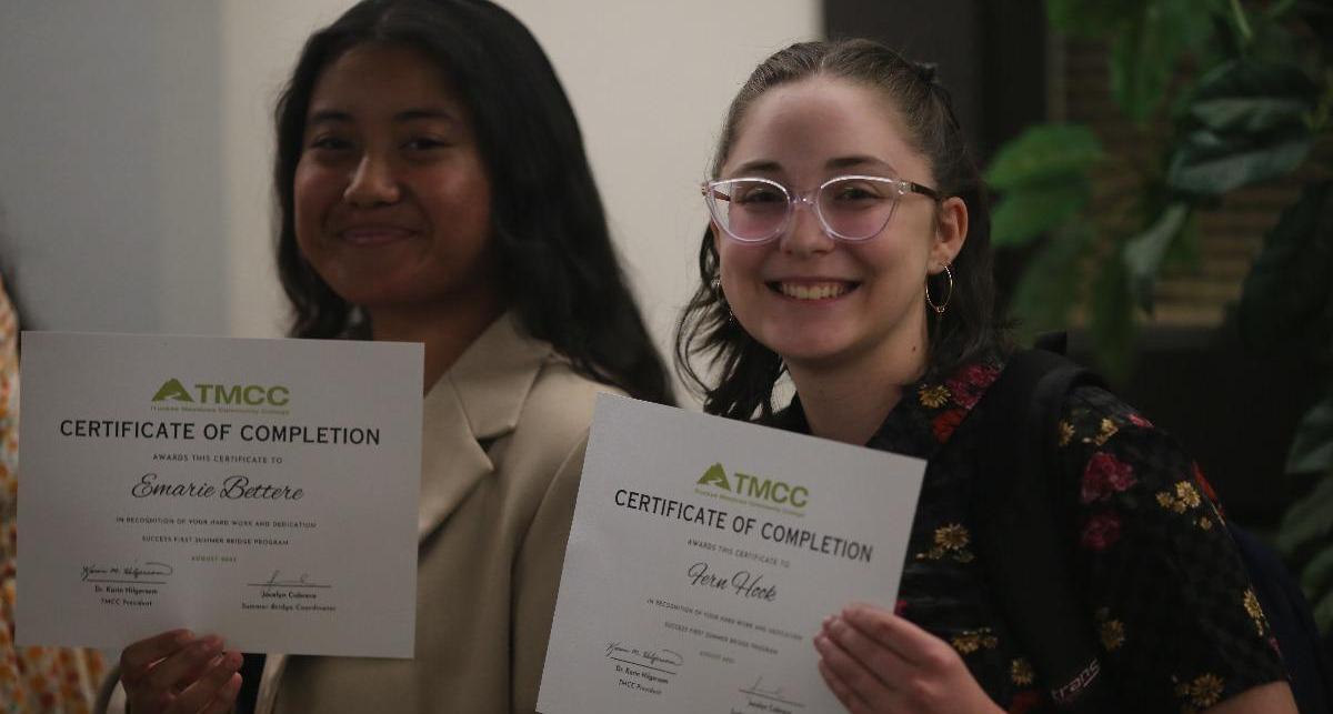 Students smile while proudly holding their certificates of completion for the Summer Bridge program.