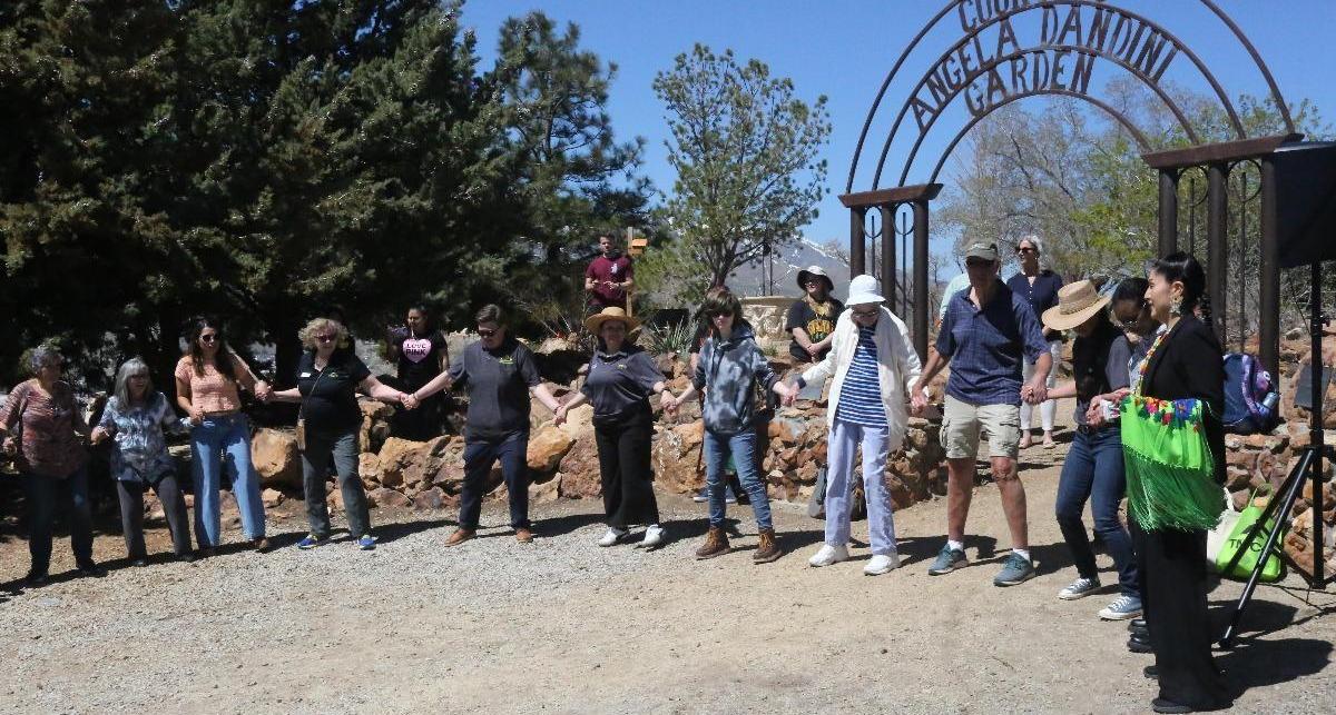 Michelle McCauley chronicles the historic and pleasant purpose of the circle dance before joining hands with the others to complete it.