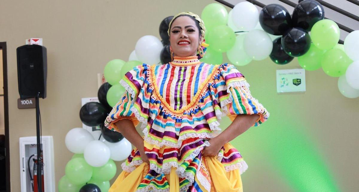 A beaming performer models her vibrant Latina huipil blouse.