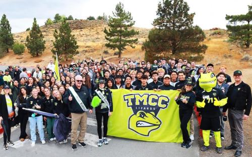 A large, smiling group of TMCC students, leadership, faculty, and staff, including Mayor Ed Lawson of Sparks, stand united for a historic, encompassing group photo on the marching path.