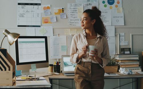 A woman pauses thoughtfully in her business office.