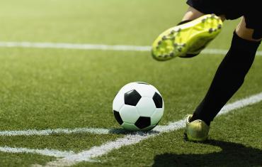 Soccer player kicking a ball on a grass field.