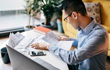 Person working on a raised desk with a calculator and paper