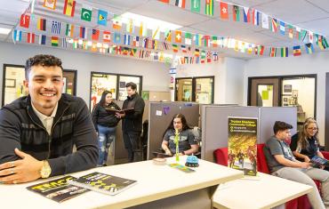 Student standing at reception area with other students around