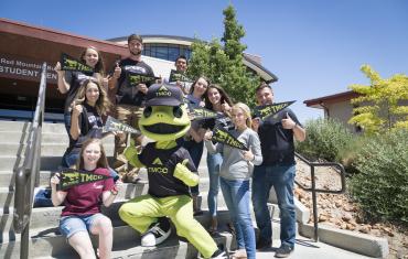 Mascot Wizard the Lizard with students on the steps of the Red Mountain Building