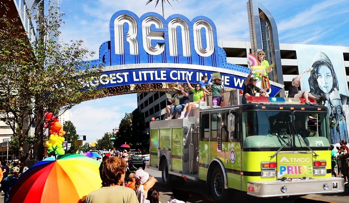 While onlookers cheer, the TMCC green firetruck, with PRIDE written in bold, rainbow letters upfront, moves under the downtown Reno archway with leadership, faculty, and students waving during the parade.