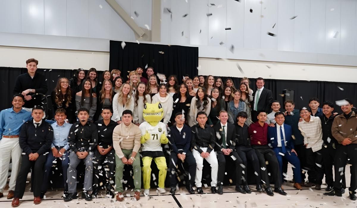 Student-athletes from the Men's and Women's Soccer teams pose for a photo with their coaches and Mighty the Lizard while confetti falls.