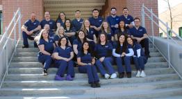 The 2024 Radiologic Technology class smiles while seated, wearing navy blue scrubs, posing for a photograph on the steps of the William N. Pennington Health Science Center.