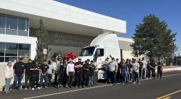 Students, faculty, staff, and partners smile for a group photo beside a milky driver's truck cabin adorning the TMCC logo on the street outside the William N. Pennington Technology Center.