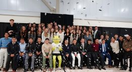 Student-athletes from the Men's and Women's Soccer teams pose for a photo with their coaches and Mighty the Lizard while confetti falls.