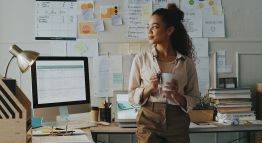 A woman pauses thoughtfully in her business office.