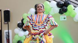 A beaming performer models her vibrant Latina huipil blouse.